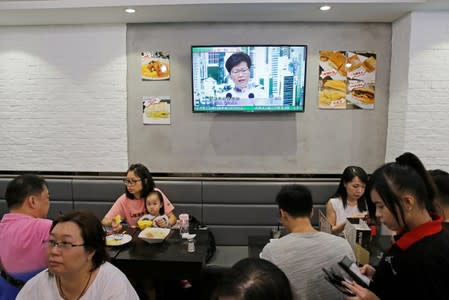 People sit at a restaurant as a news conference of Hong Kong Chief Executive Carrie Lam is broadcasted in TV in Hong Kong