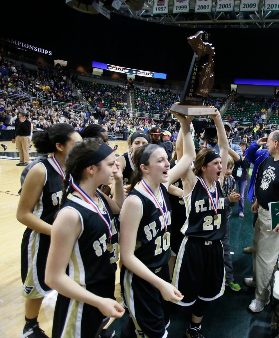 St. Ignace's players hoist the championship trophy after their 64-60 overtime win over Pittsford in the MHSAA Class D girls basketball final on Saturday, March 21, 2015 in East Lansing.