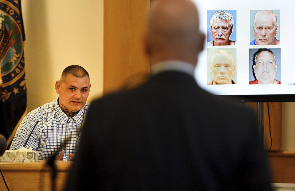 Michael Gilpatrick of Nashua, a former youth detention center resident, fights back tears as testifies during a civil trial seeking to hold the state accountable for alleged abuse at the Sununu Youth Services Center, formerly called the Youth Development Center, Wednesday, April 17, 2024, at Rockingham County Superior Court in Brentwood, N.H. In the foreground asking questions is plaintiff's attorney Rus Rilee. On the screen is so called "hit squad" members including Bradley Asbury, clockwise from to left, James Woodlock, Stephen Murphy and Jeffrey Buskey. All four are charged with sexual assault or being an accomplice to the assault against plaintiff Michael Gilpatrick. (David Lane/Union Leader via AP)