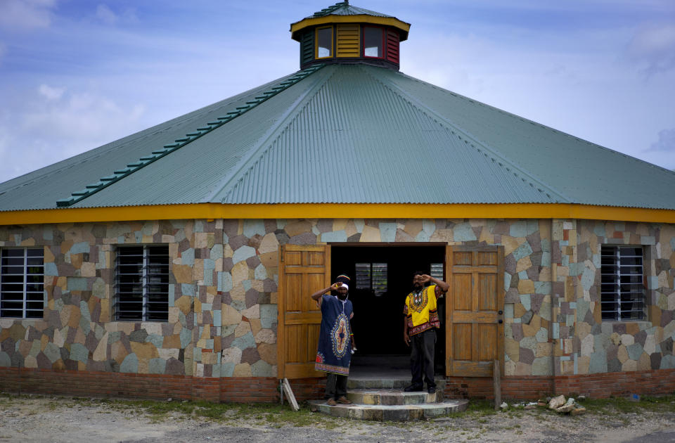 Ras Tashi, a priest with the Ras Freeman Foundation for the Unification of Rastafari, left, and fellow member Ras Wilkins, stand for a portrait at the entrance of the tabernacle on Sunday, May 14, 2023, in Liberta, Antigua. The Rastafari tabernacle sits on an old plantation where their enslaved ancestors were forced to plant sugar cane, and where they now legally grow and ritualistically smoke marijuana. (AP Photo/Jessie Wardarski)