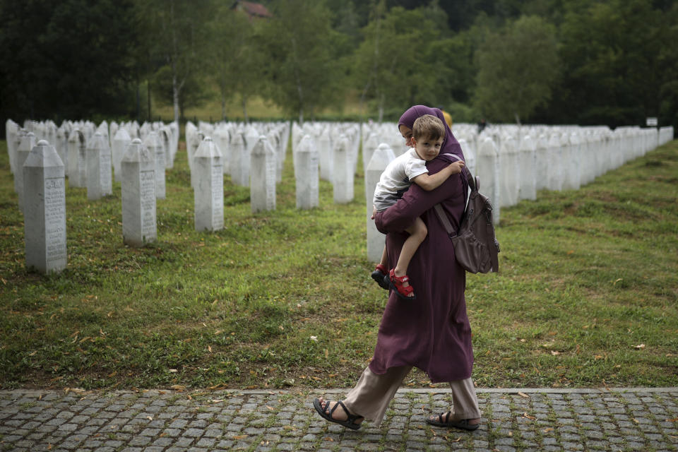 A woman walks with her child in the Memorial centre in Potocari, Bosnia, Friday, July 8, 2022. After surviving the 1995 Srebrenica massacre in which over 8,000 of their male relatives were killed, women from the small town in eastern Bosnia dedicated the remaining years of their lives to the re-telling of their trauma to the World, honoring the victims and bringing those responsible for the killings to justice. (AP Photo/Armin Durgut)