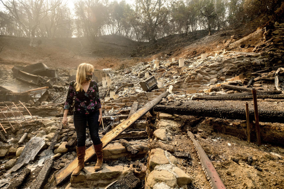 Pam, who declined to give a last name, examines the remains of her partner's Vacaville, Calif., home on Friday, Aug. 21, 2020. The residence burned as the LNU Lightning Complex fires ripped through the area Tuesday night. (AP Photo/Noah Berger)