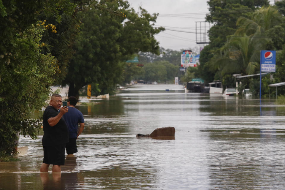 Men wade through a flooded street after the passing of Iota in La Lima, Honduras, Wednesday, Nov. 18, 2020. Iota flooded stretches of Honduras still underwater from Hurricane Eta, after it hit Nicaragua Monday evening as a Category 4 hurricane and weakened as it moved across Central America, dissipating over El Salvador early Wednesday. (AP Photo/Delmer Martinez)