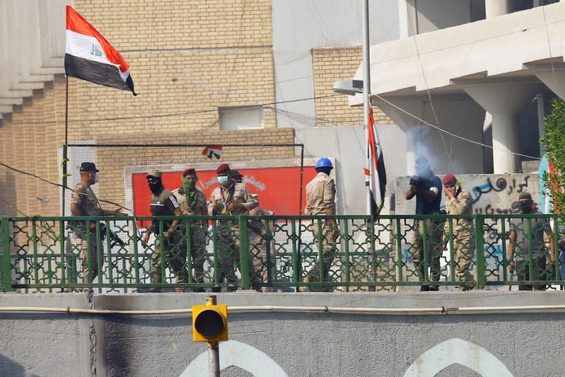 A member of Iraqi security forces points his gun towards the demonstrators during the ongoing anti-government protests in Baghdad