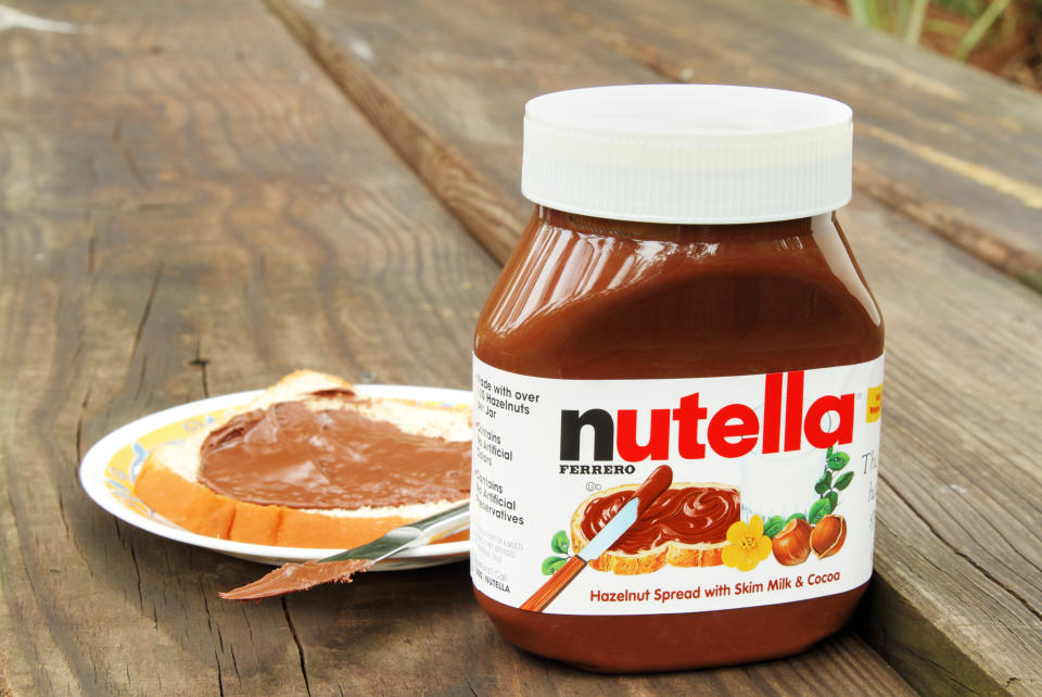 West Palm Beach, USA - October 27, 2011: Product shot of a container of Nutella hazelnut and cocoa spread. A saucer with a slice of bread freshly spread with a layer of Nutella is in the background.