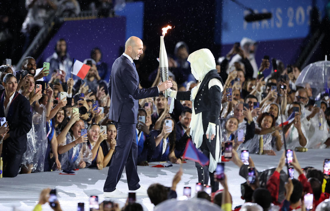 PARIS, FRANCE - JULY 26: Former footballer Zinedine Zidane carries the torch during the opening ceremony of the Olympic Games Paris 2024 on July 26, 2024 in Paris, France. (Photo by Hector Vivas/Getty Images)