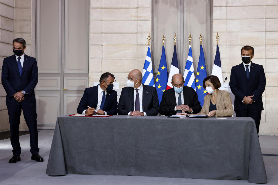 From the left, Greek Prime Minister Kyriakos Mitsotakis, Greek Defence Minister Nikolaos Panagiotopoulos, Greek Foreign Affairs Minister Nikos Dendias, French Foreign Affairs Minister Jean-Yves Le Drian, French Defense Minister Florence Parly and French President Emmanuel Macron take part in the signing ceremony of a new defence deal at The Elysee Palace Tuesday, Sept. 28, 2021. France and Greece announced on Tuesday a major, multibillion-euro defense deal including Athens' decision to buy three French warships. (Ludovic Marin, Pool Photo via AP)
