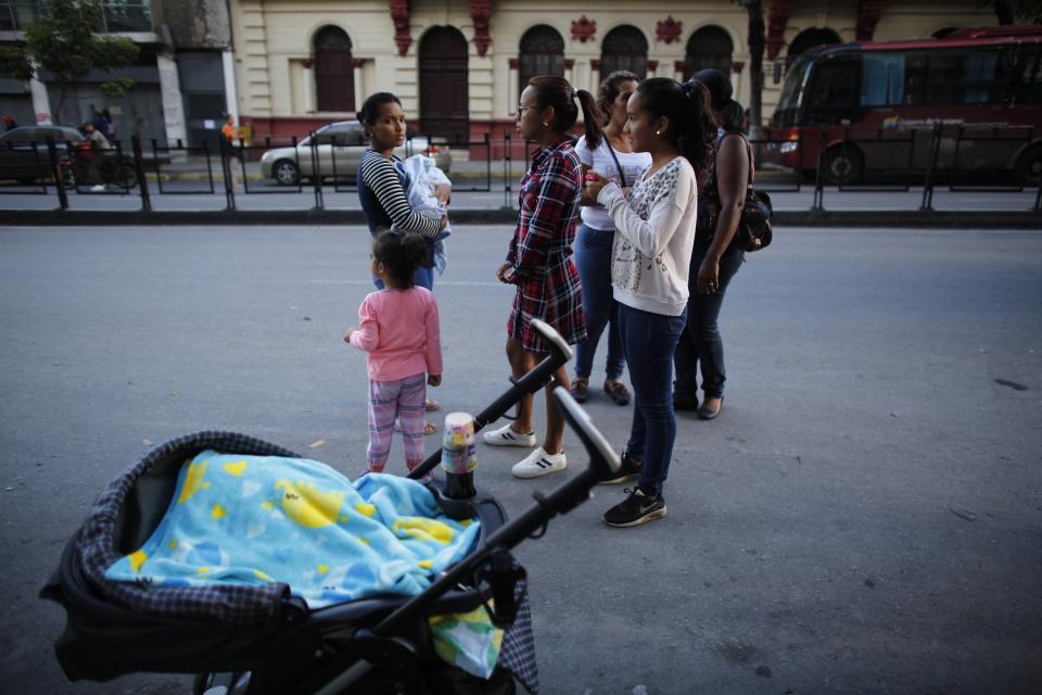 Residents stand outside after a powerful earthquake shook eastern Venezuela, causing buildings to be evacuated in the capital of Caracas, Venezuela, Tuesday, Aug. 21, 2018. The quake was felt as far away as Colombia's capital and in the Venezuelan capital office workers evacuated buildings and people fled homes. (AP Photo/Ariana Cubillos)