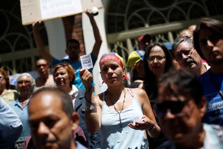 An opposition supporter holds a flyer as she attends a rally against the National Constituent Assembly, outside a school where a polling center will be established for a Constitutional Assembly election next Sunday, in Caracas, Venezuela, July 24, 2017. The flyer reads "The dictatorship always lies. We live in queues. And now the Constitutional rubbish." REUTERS/Andres Martinez Casares