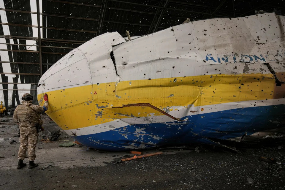 A Ukrainian serviceman touches the nose of the destroyed Antonov An-225 Mriya aircraft.
