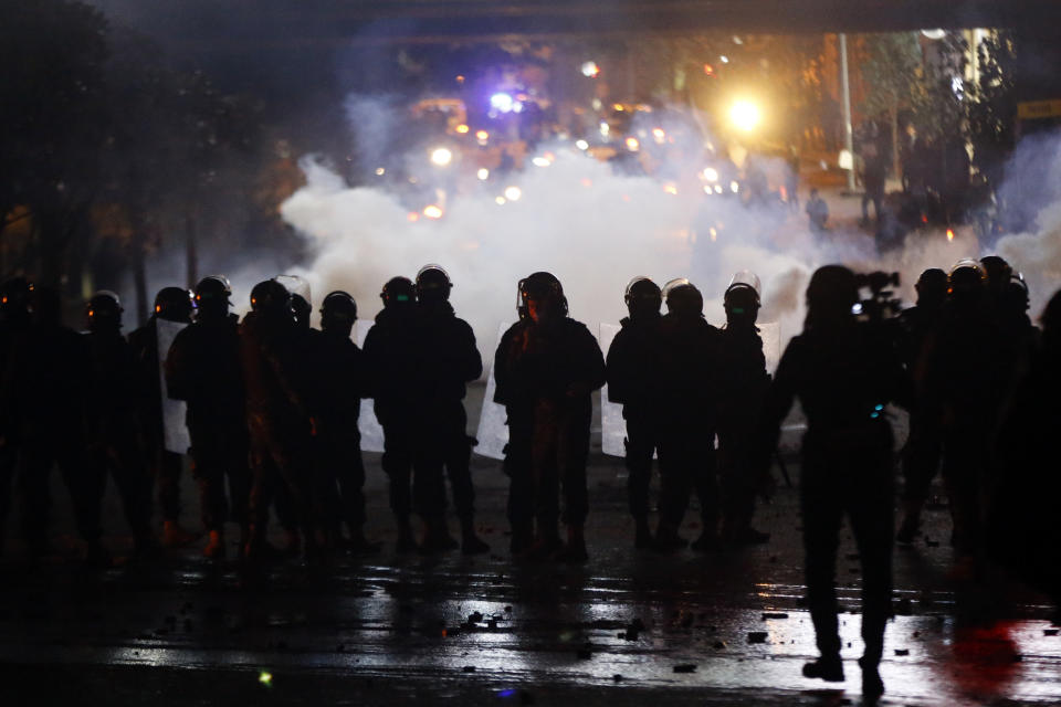 Lebanese riot police fire tear gas towards supporters of the Shiite Hezbollah and Amal groups in Beirut, Lebanon, Tuesday, Dec. 17, 2019. Supporters of Lebanon's two main Shiite groups Hezbollah and Amal have clashed with security forces and set fire to cars in Beirut in a third consecutive night of violence in the capital. The unrest early Tuesday apparently was triggered by a video circulating online that shows a man insulting Shiite and religious figures. (AP Photo/Bilal Hussein)