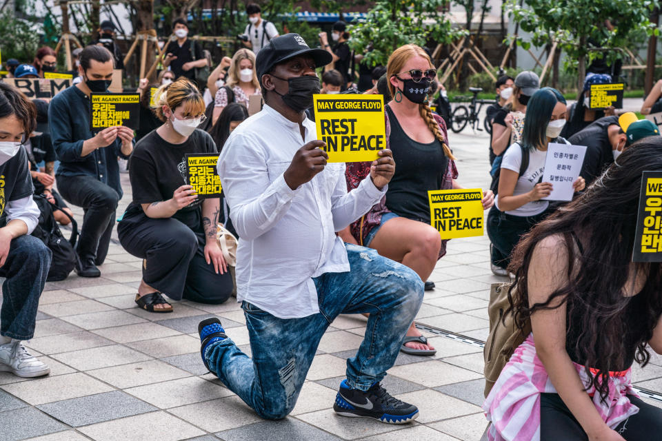 SEOUL, SOUTH KOREA - 2020/06/06: Protesters wearing protective masks kneel and hold 'May George Floyd Rest In Peace' and 'We Against Racism' placards during the demonstration. Thousands in Seoul support U.S. protests against police brutality that caused the May 25th murder of George Floyd in Minneapolis. (Photo by Simon Shin/SOPA Images/LightRocket via Getty Images)