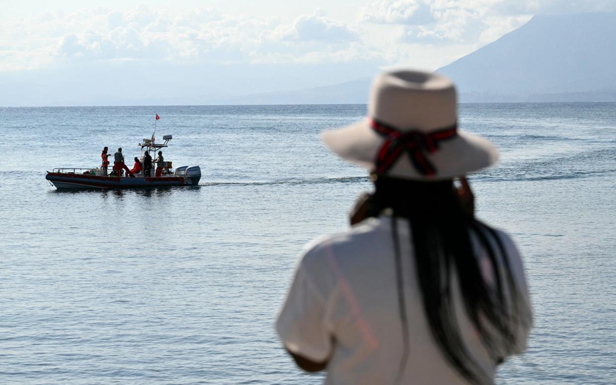 A woman watches rescue teams at work in Porticello near Palermo