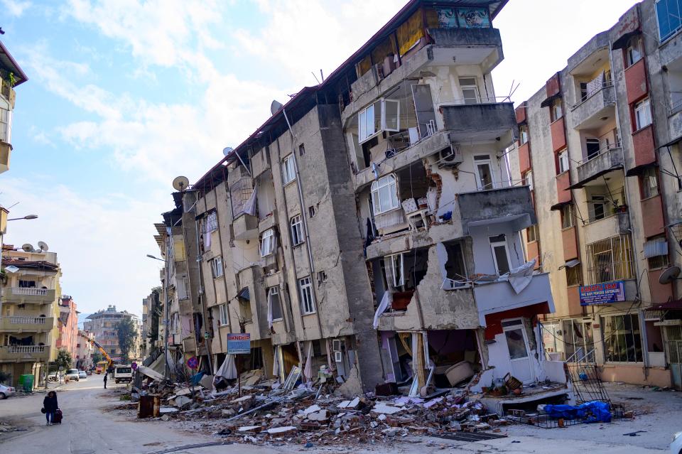 TOPSHOT - A local resident walks past a destroyed building in Hatay, on February 11, 2023, after a 7.8-magnitude earthquake struck the country's southeast. - Rescuers pulled out children on February 10, 2023, from the rubble of the Turkey-Syria earthquake that struck on February 6, 2023, as the toll approached 23,000 and a winter freeze compounded the suffering for nearly one million people estimated to be in urgent need of food. (Photo by Yasin AKGUL / AFP) (Photo by YASIN AKGUL/AFP via Getty Images)
