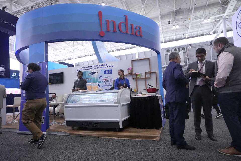 People gather near an exhibit booth for India's Marine Products Export Development Authority at the North American Seafood Expo, Monday, March 11, 2024, in Boston. (AP Photo/Steven Senne)