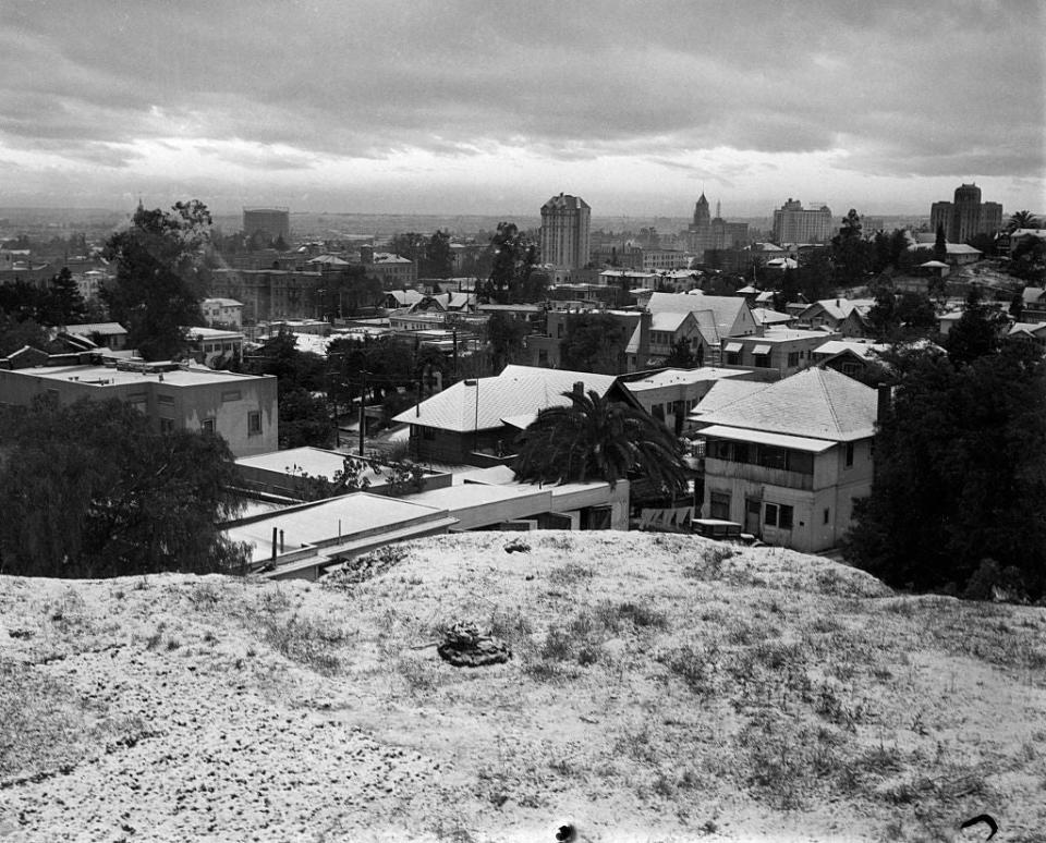 1932-Hollywood, CA- View of Hollywood Hills during recent snow storm. Hollywood in 1930s. View of side of mountains with streets, palm trees, street lamps, houses and buildings.
