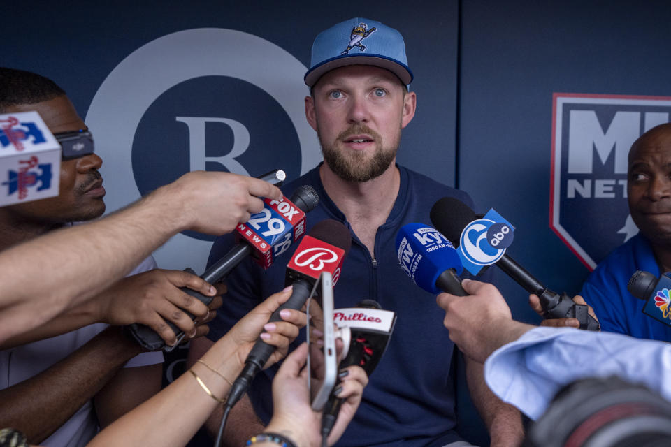 Milwaukee Brewers' Rhys Hoskins, center, takes questions from the media prior to a baseball game against the Philadelphia Phillies, Monday, June 3, 2024, in Philadelphia. (AP Photo/Chris Szagola)