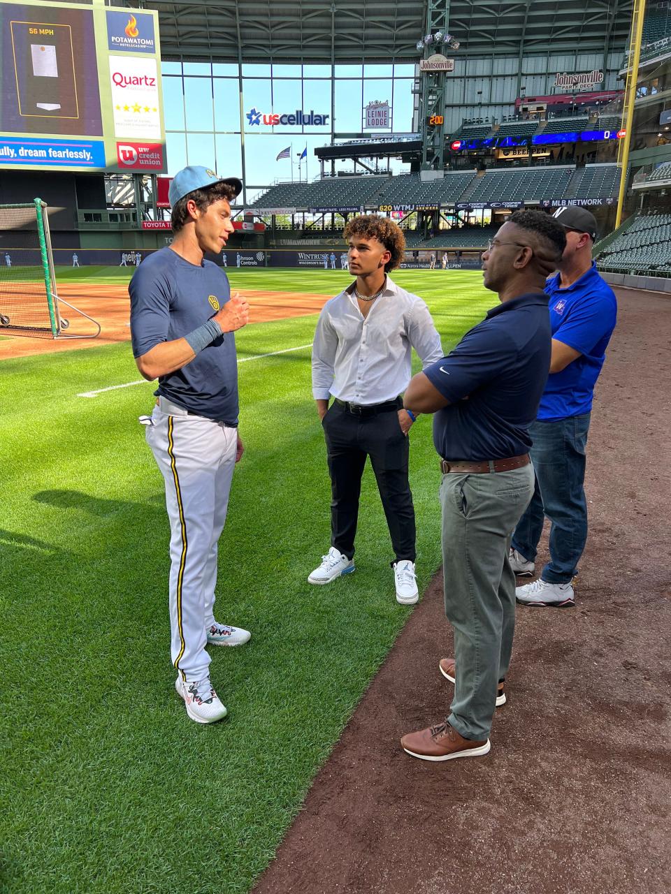 Eric Brown Jr., the Milwaukee Brewers' top pick in the 2022 Major League Baseball draft, chats with left fielder Christian Yelich before the Brewers' game against the Colorado Rockies last July at American Family Field in Milwaukee.