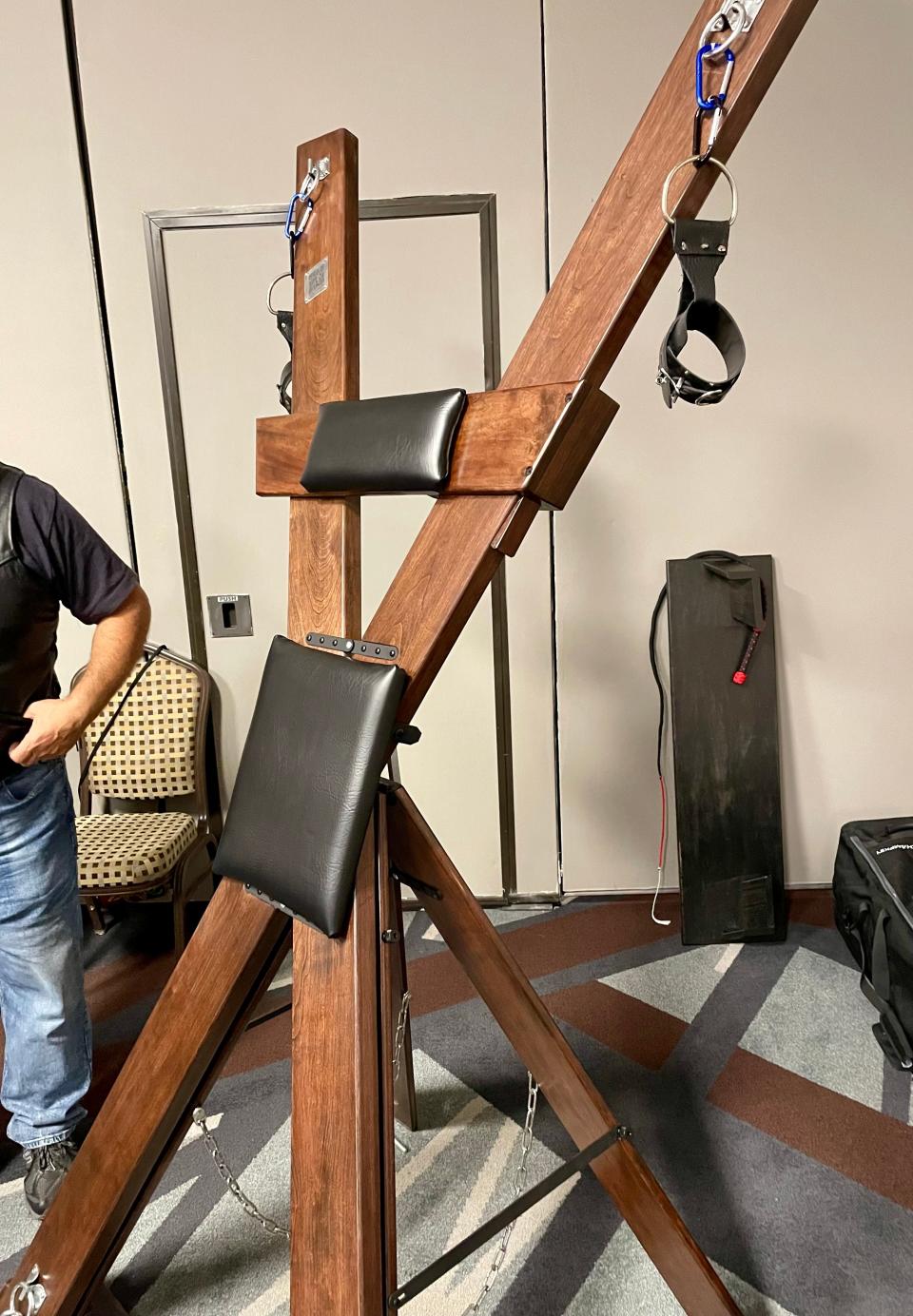An X-frame made of wood and leather to be used in a BDSM dungeon was on sale from a vendor in April 2024 at the Rochester Erotic Arts Festival.