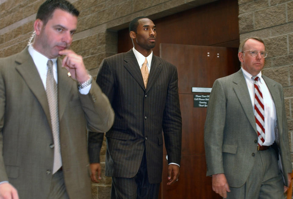 FILE - In this Wednesday, March 24, 2004, file photo, Los Angeles Lakers' Kobe Bryant, center, walks out of a holding area as he prepares to leave for a lunch break from proceedings in his sexual assault case as members of his security team accompany him, in Eagle, Colo. Some argued that there was no need to dredge up accounts of the 2003 rape allegation against Bryant when he died suddenly Sunday, Jan. 26, 2020. Others viewed it as another example of an icon being given a pass because he was a successful athlete. (AP Photo/Ed Andrieski, File)