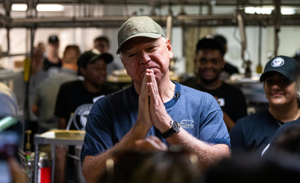 Jeff Bezos stands in a busy kitchen with hands clasped, surrounded by smiling staff