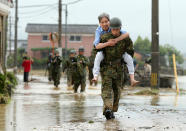 <p>Japanese soldiers help local residents evacuate from flooded area in Asakura, Fukuoka prefecture, on July 6, 2017. More than a dozen people are missing after huge floods swept away houses in southern Japan, tearing up roads as roiling waters surged through villages, authorities said, after unprecedented rainfall.(Photo: STR/AFP/Getty Images) </p>