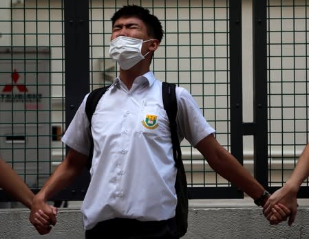 A secondary school student shouts slogans as he joins a human chain demonstrating against what the students say is police brutality against protesters, after clashes at Wan Chai district in Hong Kong