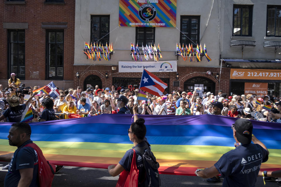 A unit passes the Stonewall Inn with a rainbow banner during the LBGTQ Pride march Sunday, June 30, 2019, in New York. (AP Photo/Craig Ruttle)
