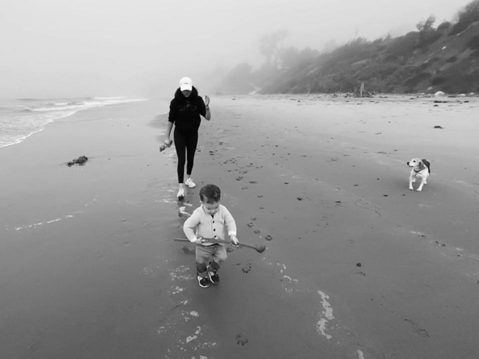 A black and white screenshot of Meghan Markle with Archie on the beach in California