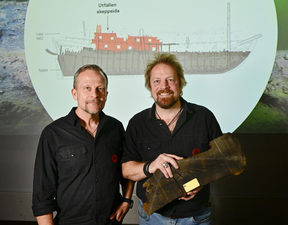 Divers Patrik Hoglund and Jim Hansson, right, marine archaeologists at Vrak – Museum of Wrecks hold a piece of wood from the found shipwreck The Apple in Stockholm, Sweden, Monday, Oct. 24, 2022. (Jonas Ekströmer/TT News Agency via AP)