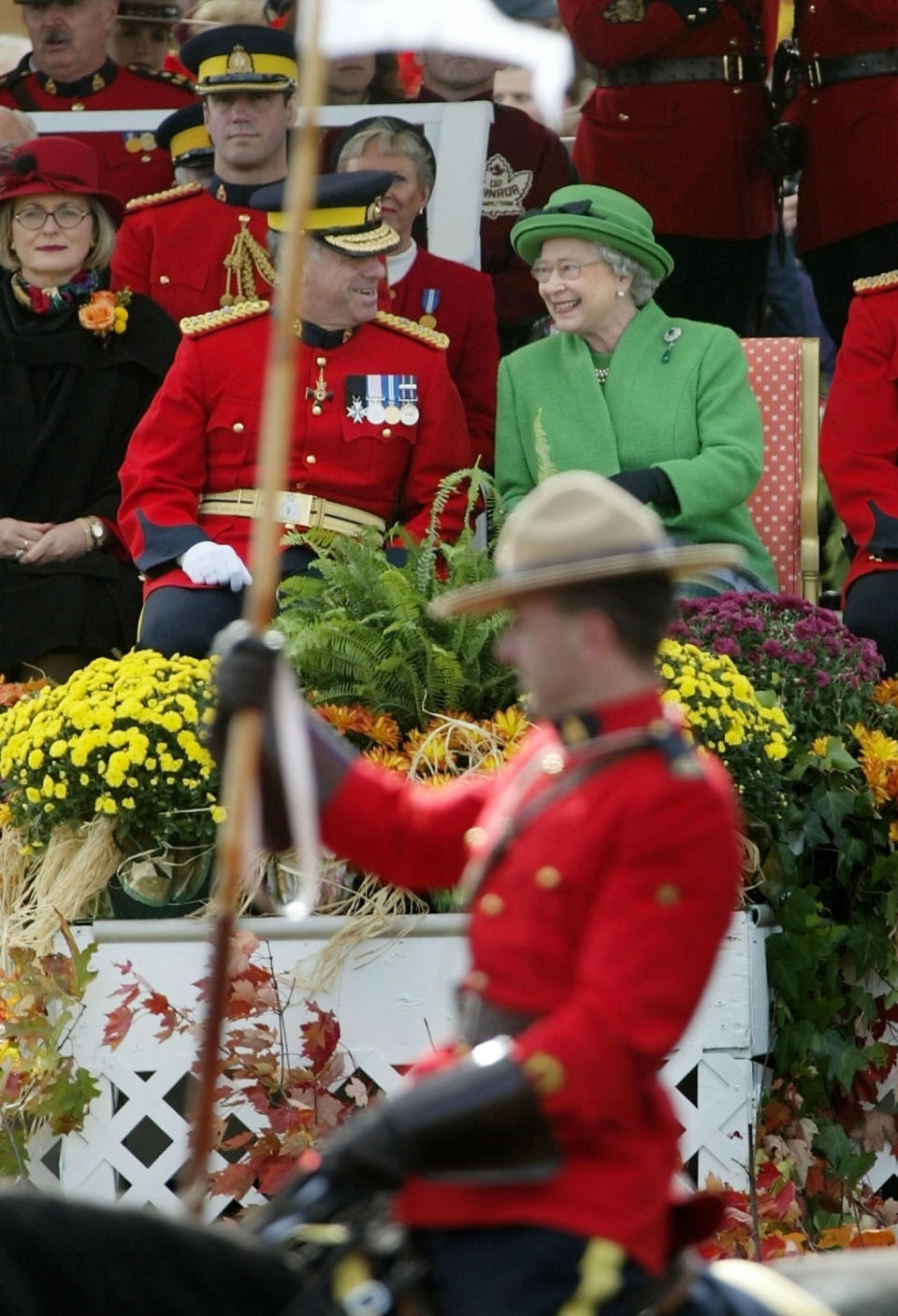Queen Elizabeth II and Royal Canadian Mounted Police Commissioner Giuliano Zaccardelli (L) share a joke while watching the RCMP Musical Ride perform at their training facility at 'N' Division in Ottawa, October 14, 2002. The Queen is on the final day of her 11-day Golden Jubilee tour of Canada. REUTERS/Andy Clark AC