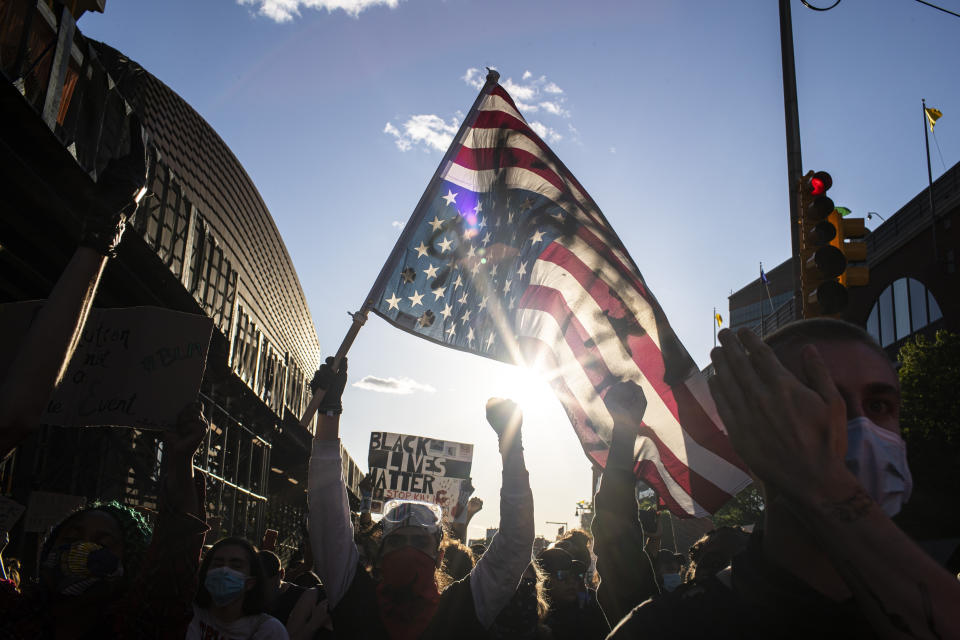 FILE - A man holds a U.S. flag upside down, a sign of distress, as protesters march down the street during a solidarity rally for George Floyd, Sunday, May 31, 2020, in the Brooklyn borough of New York. (AP Photo/Wong Maye-E, File)