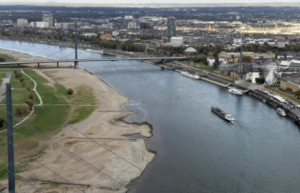In this Oct. 22, 2018 photo a cargo ship drives on the Rhine River in Duesseldorf, Germany, during historically low water levels. A hot, dry summer has left German waterways at record low levels, causing chaos for the inland shipping industry, environmental damage and billions of euros of losses _ a scenario that experts warn could portend things to come as global temperatures rise. (AP Photo/Martin Meissner)