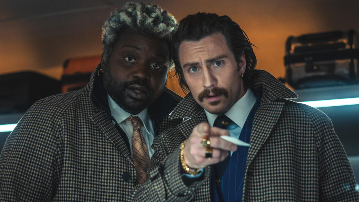  Brian Tyree Henry and Aaron Taylor-Johnson looking surprised at something right in front of them in Bullet Train. 