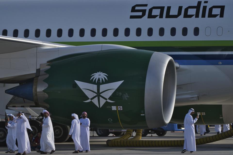 Emiratis walk past a Saudia Boeing 787 Dreamliner with a retro logo design at the Dubai Air Show in Dubai, United Arab Emirates, Monday, Nov. 13, 2023. Long-haul carrier Emirates opened the Dubai Air Show with a $52 billion purchase of Boeing Co. aircraft, showing how aviation has bounced back after the groundings of the coronavirus pandemic, even as Israel's war with Hamas clouds regional security. (AP Photo/Jon Gambrell)