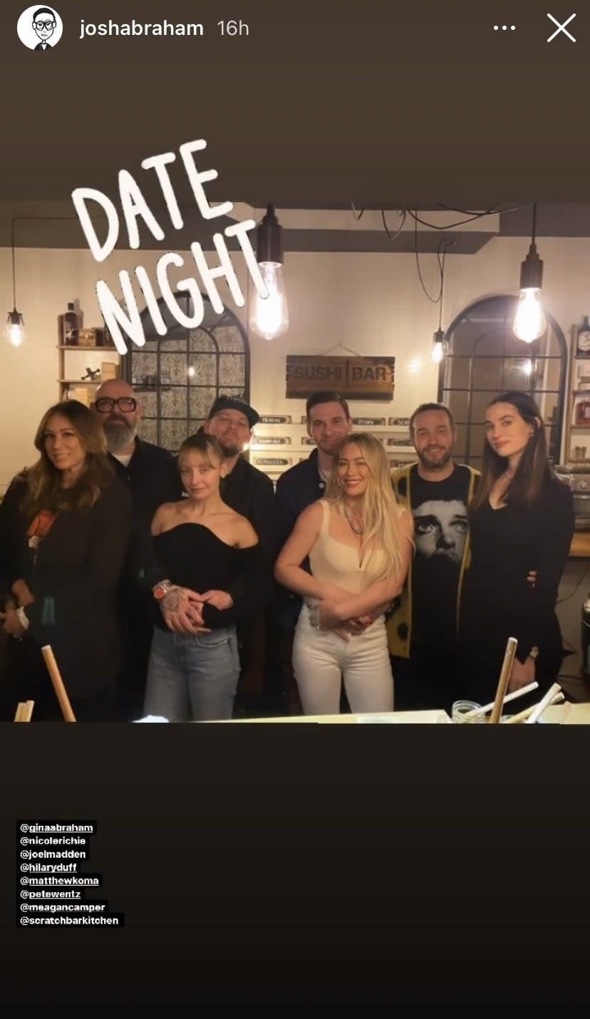 The group pose with the women standing in front of their partners in the middle of a restaurant