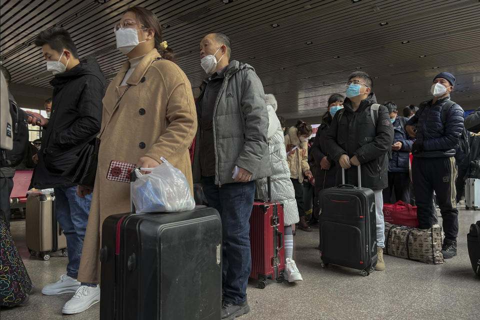 Travellers wearing face masks with their luggage prepare to catch their trains at the West Railway Station in Beijing, Friday, Jan. 6, 2023. China is seeking to minimize the possibility of a major new COVID-19 outbreak during this month's Lunar New Year travel rush following the end of most pandemic containment measures. (AP Photo/Wayne Zhang)