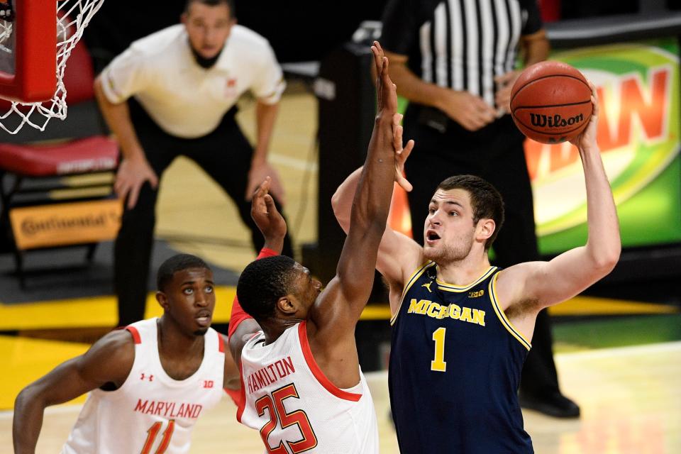 Michigan center Hunter Dickinson (1) goes to the basket next to Maryland forward Jairus Hamilton (25) and guard Darryl Morsell (11) during the first half of an NCAA college basketball game, Thursday, Dec. 31, 2020, in College Park, Md.