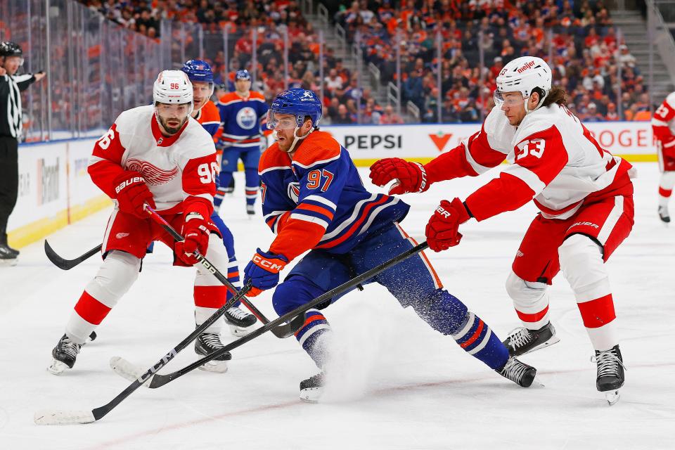 Edmonton Oilers forward Connor McDavid (97) protects the puck from Detroit Red Wings defensemen Moritz Seider (53) and defensemen Jake Walman (96) at Rogers Place in Edmonton, Alberta, on Tuesday, Feb. 13, 2024.