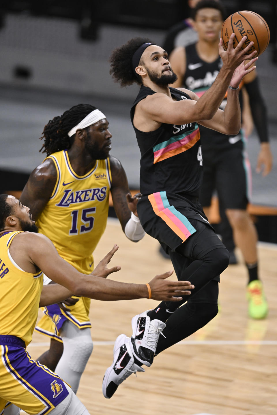 San Antonio Spurs' Derrick White (4) shoots as Los Angeles Lakers' Montrezl Harrell (15) and Talen Horton-Tucker defend during the first half of an NBA basketball game Friday, Jan. 1, 2021, in San Antonio. (AP Photo/Darren Abate)