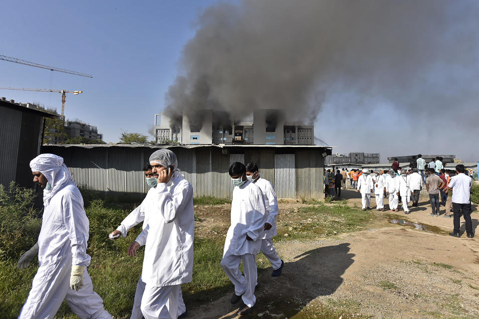 Workers wearing protective gear are seen after a fire broke out at the Serum Institute of India, in Pune, on January 21, 2021. / Credit: AFP via Getty