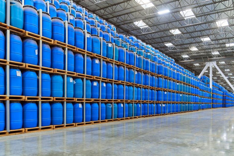 hundreds of blue barrels stacked in a factory warehouse.