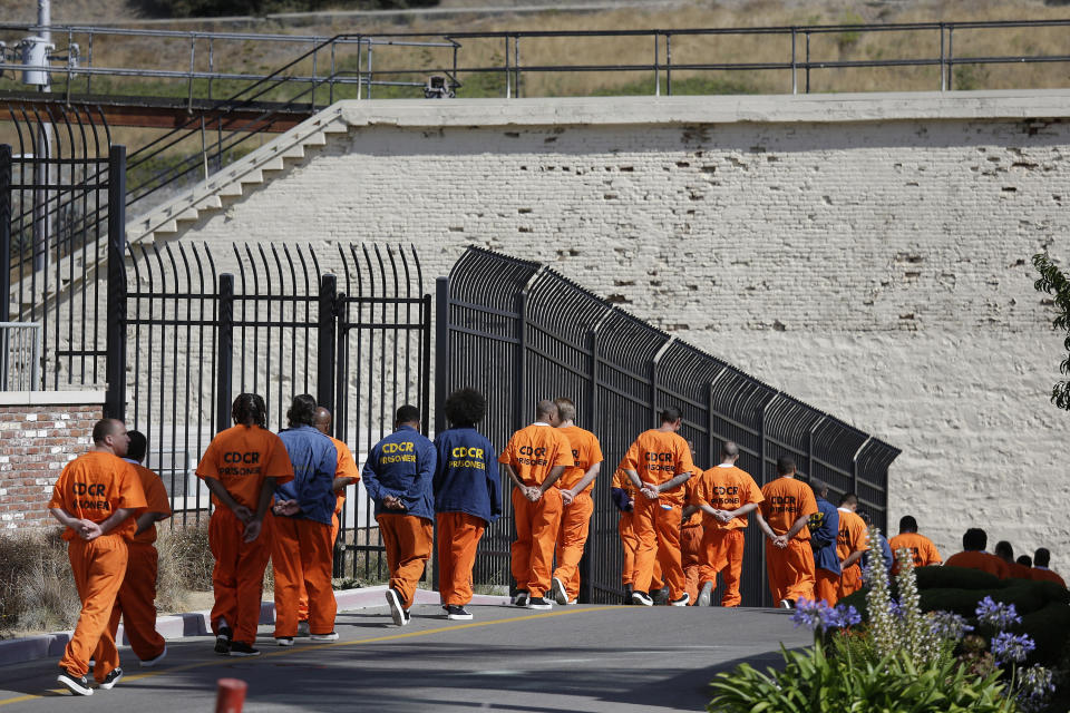 FILE - In this Aug. 16, 2016, file photo, general population inmates walk in a line at San Quentin State Prison in San Quentin, Calif. A California appeals court has ordered state corrections officials to cut the population of one of the world's most famous prisons to less than half of its designed capacity, citing officials' "deliberate indifference" to the plight of inmates during the coronavirus pandemic. State prison officials said Wednesday, Oct. 21, 2020, that they are deciding whether to appeal the order, which otherwise will force them to parole or transfer about 1,100 inmates serving time in San Quentin State Prison north of San Francisco. (AP Photo/Eric Risberg, File)