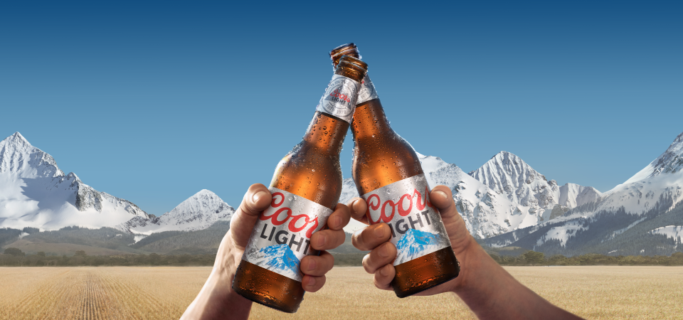 Two Coors Light bottles in front of mountains.