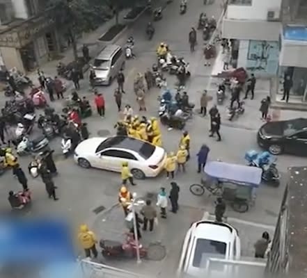 一群身穿黃衣的外送員將車子圍住。（圖／翻攝自澎湃視頻微博／東森新聞）