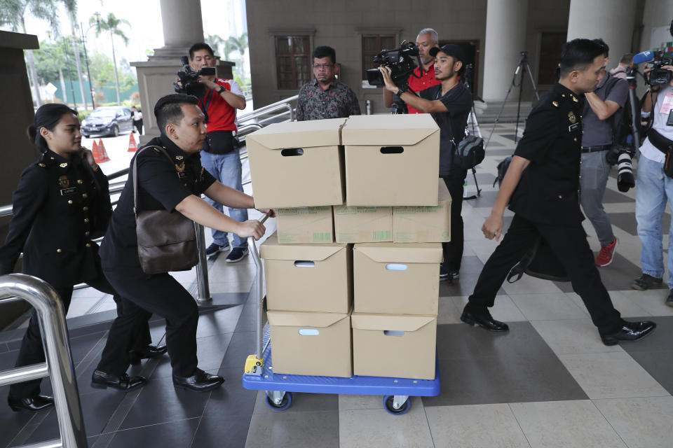 FILE - In this Wednesday, Aug. 28, 2019, file photo, Malaysian Anti-Corruption agency's staff transport documents for 1MDB case to Kuala Lumpur high court in Kuala Lumpur, Malaysia. Malaysia has ordered 80 people and groups to pay fines totaling about $100 million for allegedly receiving funds from the 1MDB state investment fund. Najib faces 42 charges of corruption, abuse of power and money laundering in five separate criminal cases linked to the multibillion-dollar looting of 1MDB. (AP Photo/Vincent Thian, File)