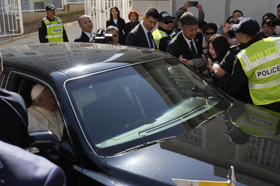 A faithful makes her way through security to reach for Pope Francis leaving in a car after a meeting with charity workers and the inauguration of the House of Mercy in Ulaanbaatar, Monday, Sept. 4, 2023. Francis toured the House of Mercy in the final event of an historic four-day visit to a region where the Holy See has long sought to make inroads. (AP Photo/Ng Han Guan)