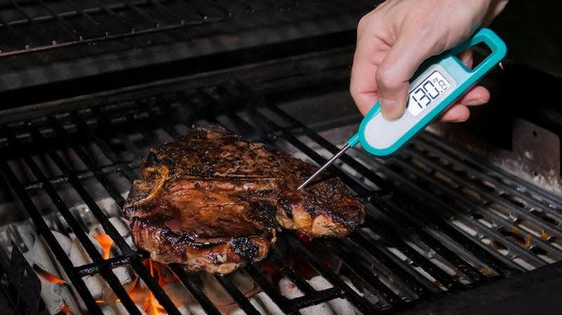 Checking meat temperature on grill with digital thermometer