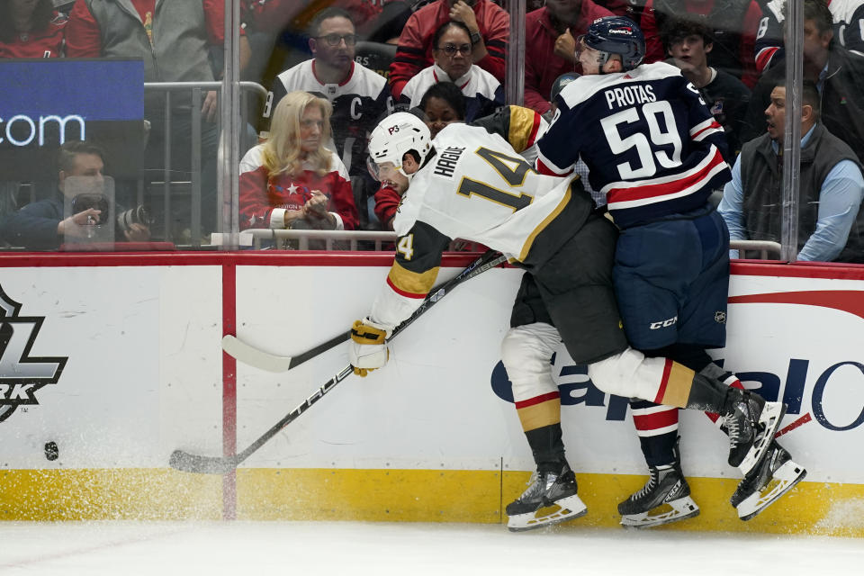 Vegas Golden Knights defenseman Nicolas Hague (14) and Washington Capitals center Aliaksei Protas chase after the puck in the third period of an NHL hockey game, Tuesday, Nov. 1, 2022, in Washington. (AP Photo/Patrick Semansky)