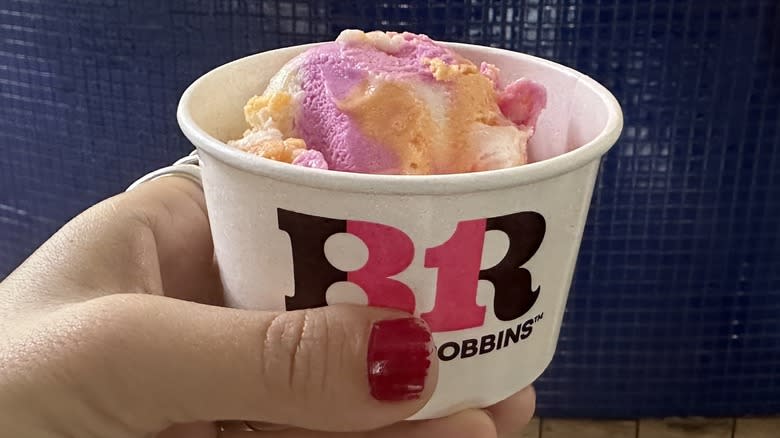 Hand holding rainbow sherbet in cup